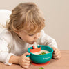 Toddler holding Teal Baby care Bowl and Independent Sipping Soup and Puree through the Wide Silicone Straw Attachment