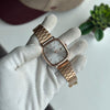 Rose gold watch held by a gloved hand with a blurred background