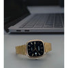 Gold Casio watch on a surface with a laptop in the background